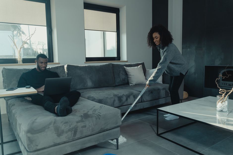 Couple sharing household chores in a stylish living room, blending comfort and cooperation.